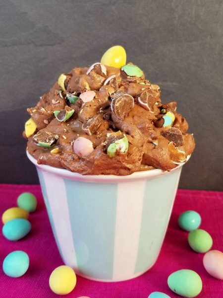 a pink and blue cup of creamy chocolate cheesecake with easter chocolate eggs