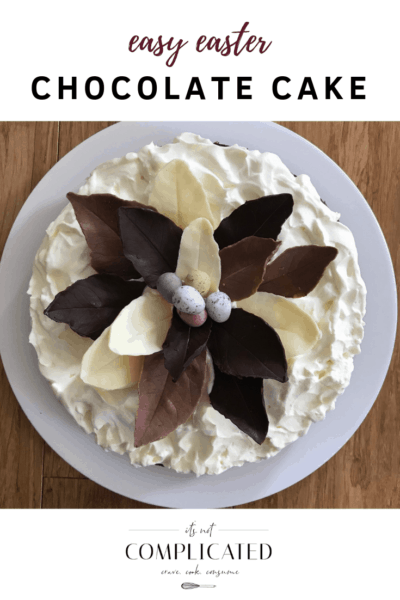 white frosted cake with homemade chocolate leaves on top