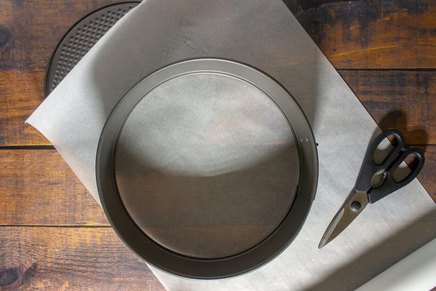 a springform pan with parchment paper and scissors
