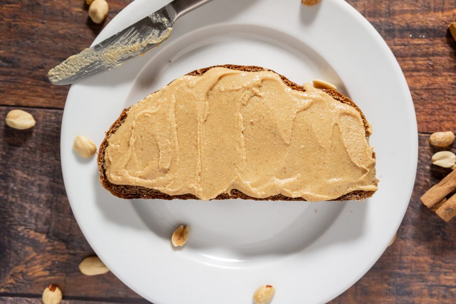 A plate with a slice of bread topped with peanut butter