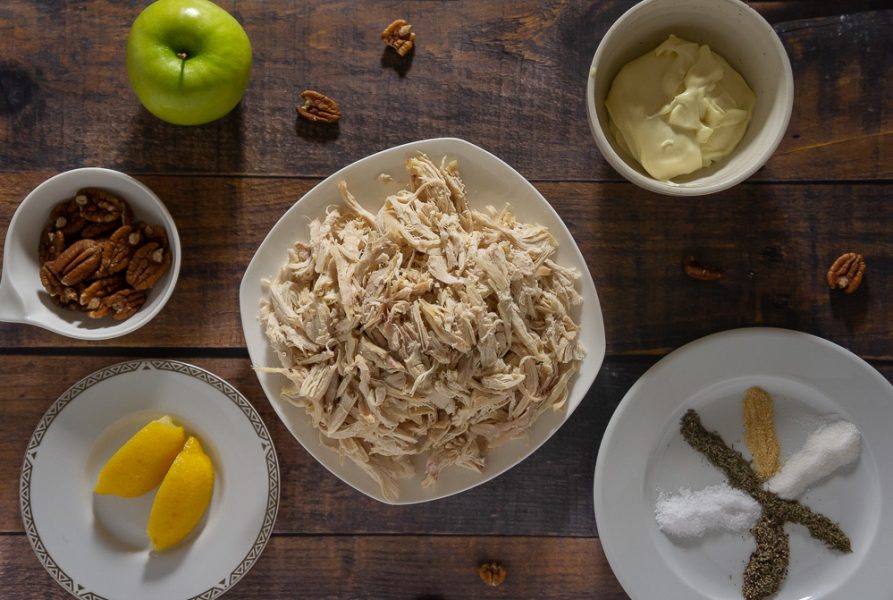 Shredded chicken, a green apple, lemon wedges, pecans, mayo and spices