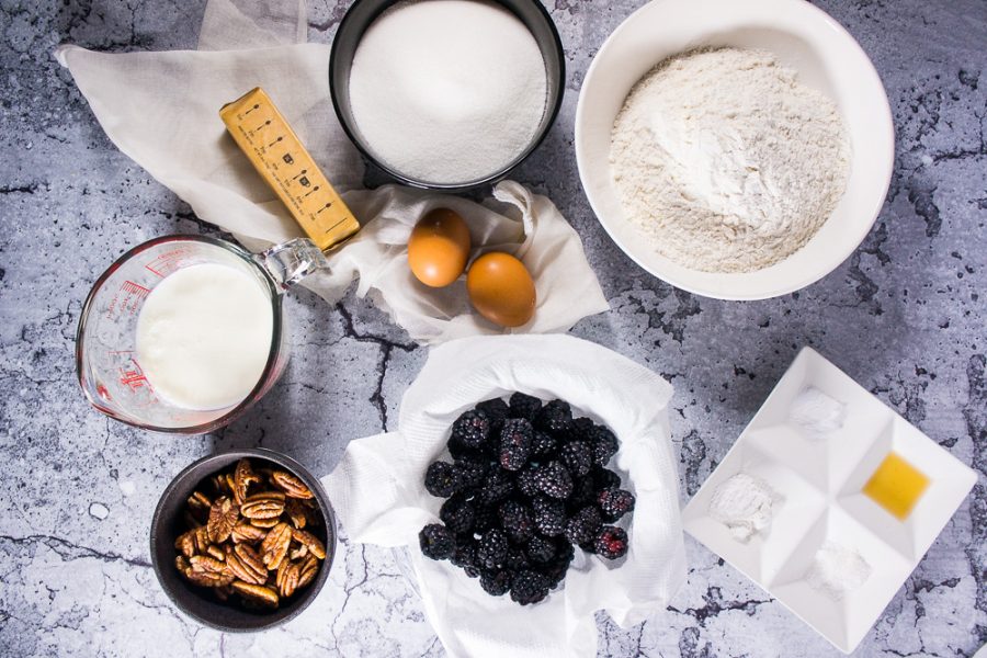 Blackberries, sugar, flour, buttermilk, eggs, butter, and pecans in different bowls.