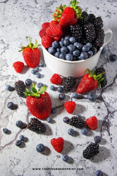 A white bowl with blueberries, raspberries, blackberries, and strawberries 