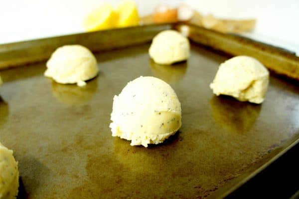 Portioning chewy lemon sugar cookies onto a metal baking sheet. 