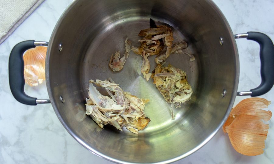 A stock pot with chicken carcasses at the bottom
